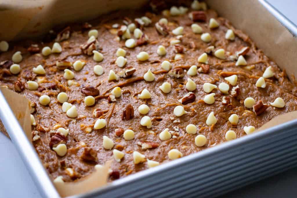 Sourdough blondie batter with extra chocolate chips and pecans on top, ready to bake.
