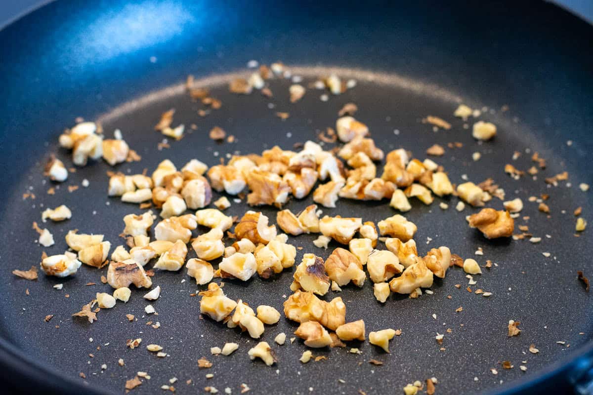 A handful of chopped walnuts toasting in a dry pan.