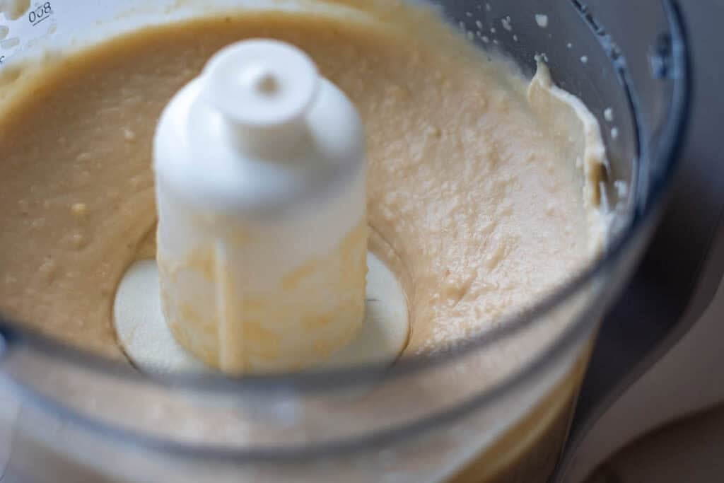 Close-up of blended butter bean dip in food processor.