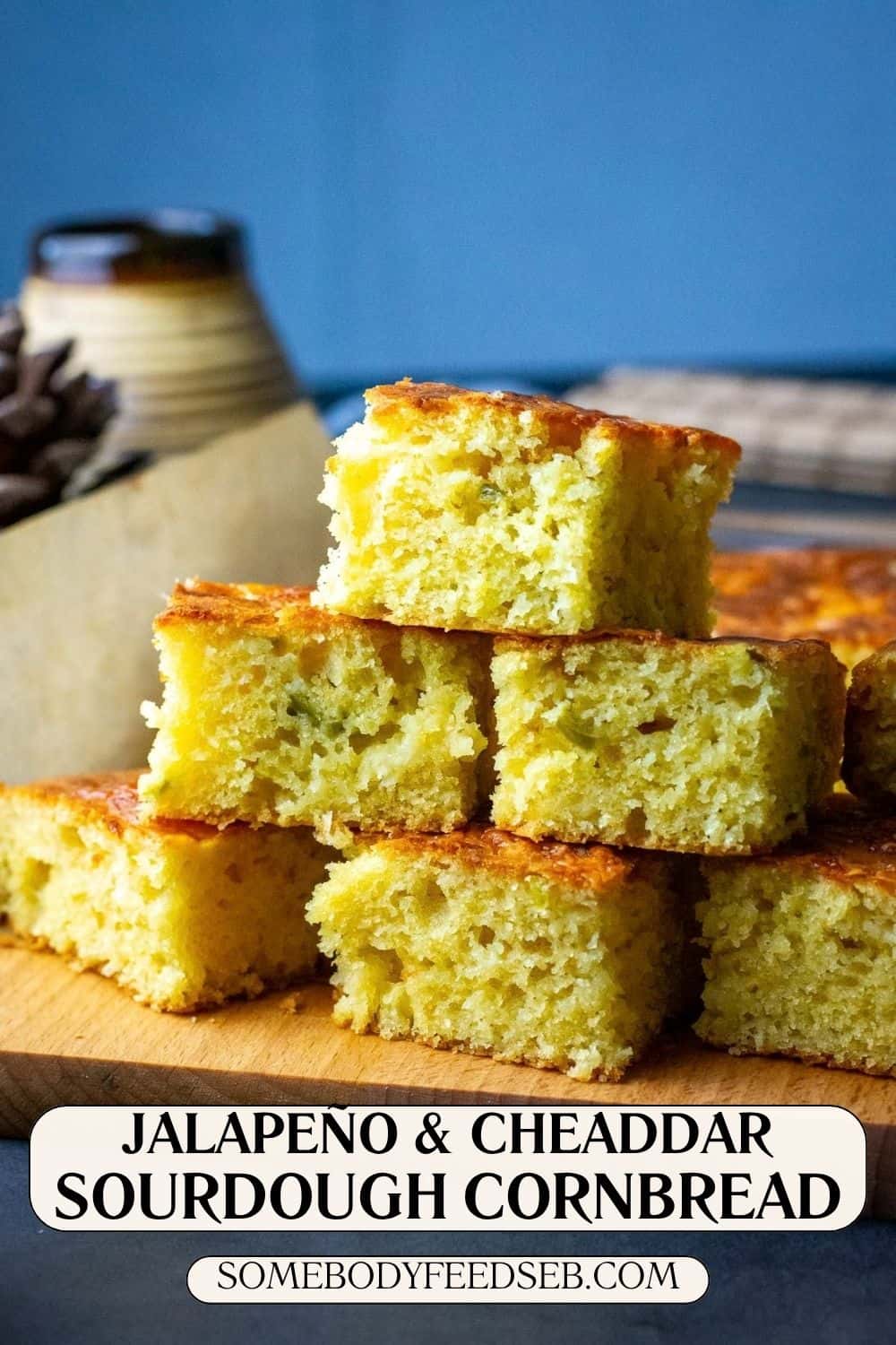 A stack of jalapeno and cheddar sourdough cornbread squares on a wooden board. Pin for Pinterest.