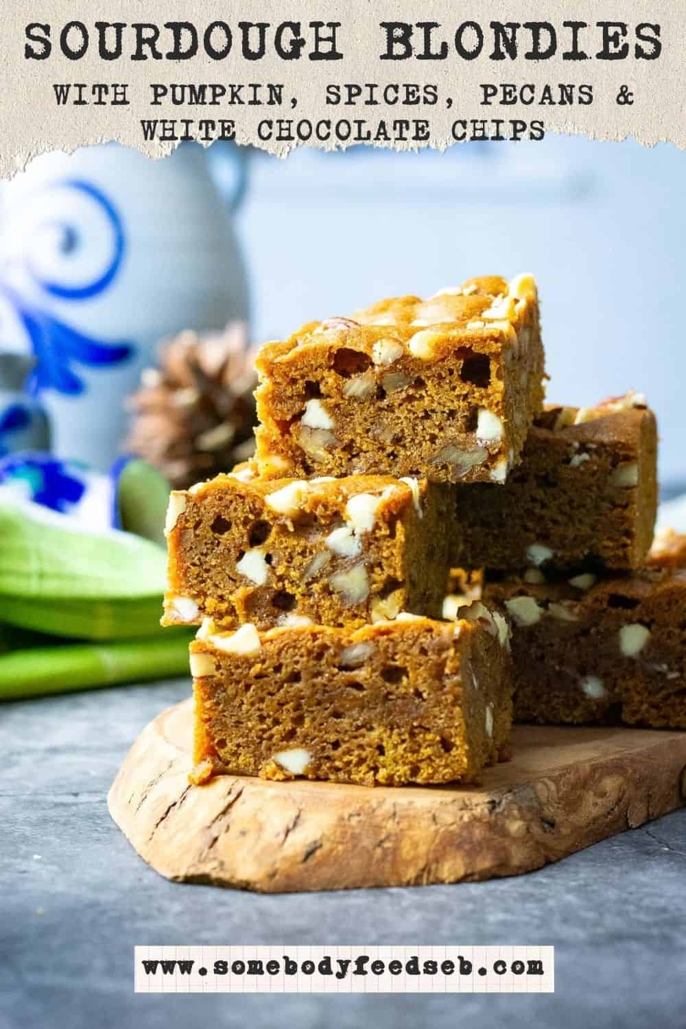 A stack of chai-spiced sourdough pumpkin blondies with pecans and white chocolate on a decorative wooden board. Pin for Pinterest.