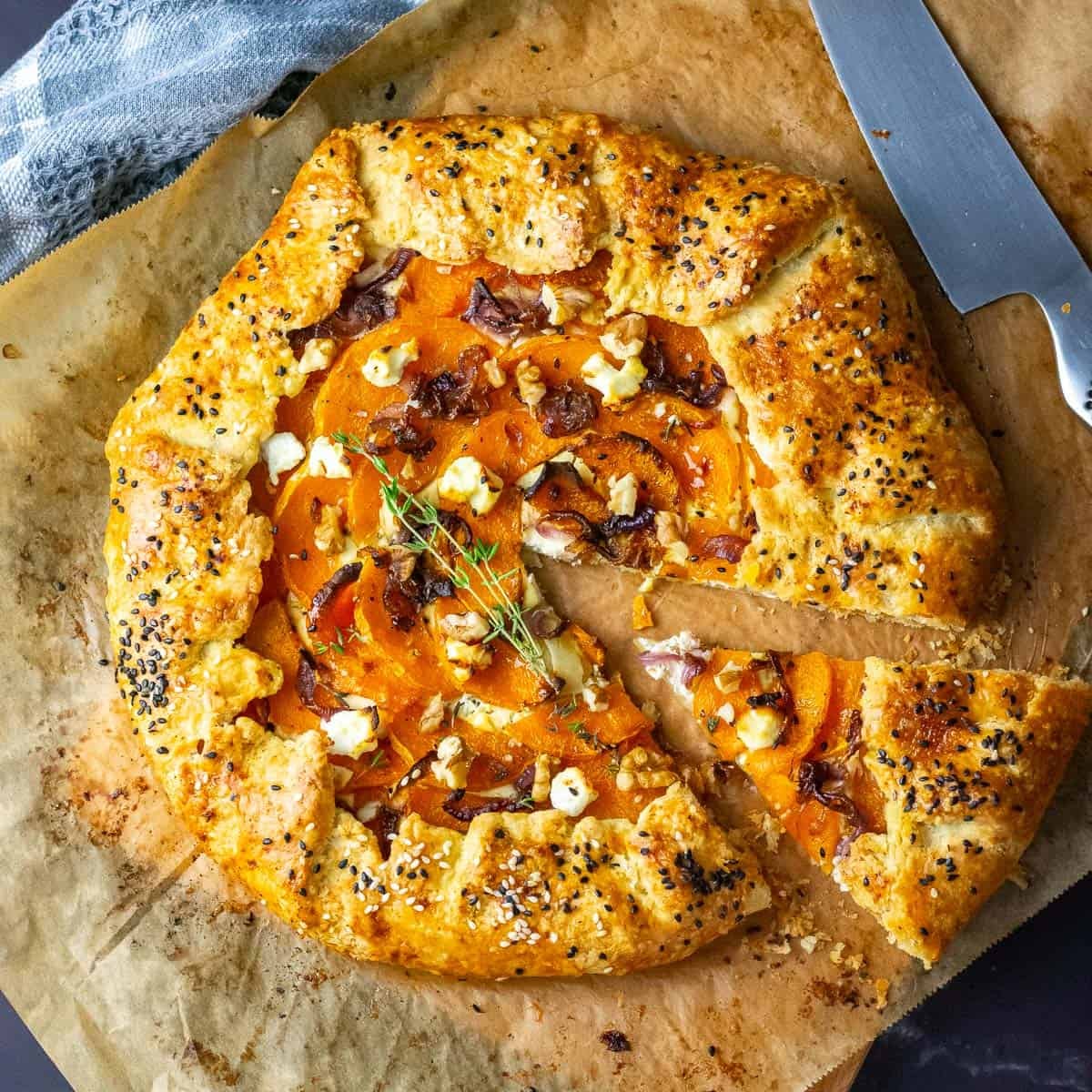 Butternut Squash Sourdough Galette with one slice cut on a piece of parchment paper.