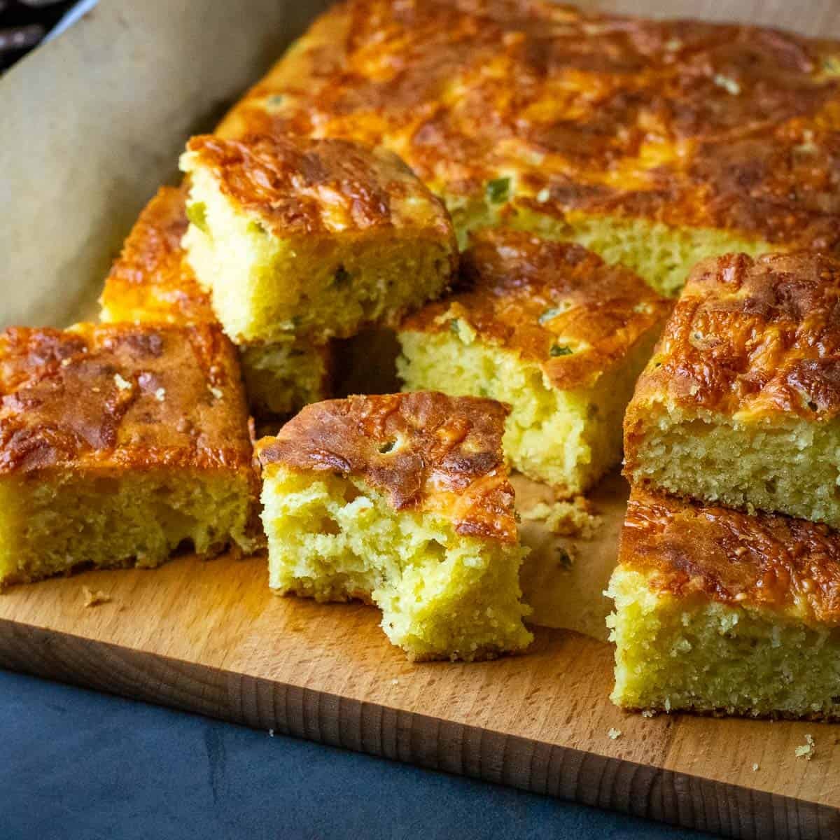 Jalapeno Cheddar Sourdough Cornbread cut into squares with one square bitten into.