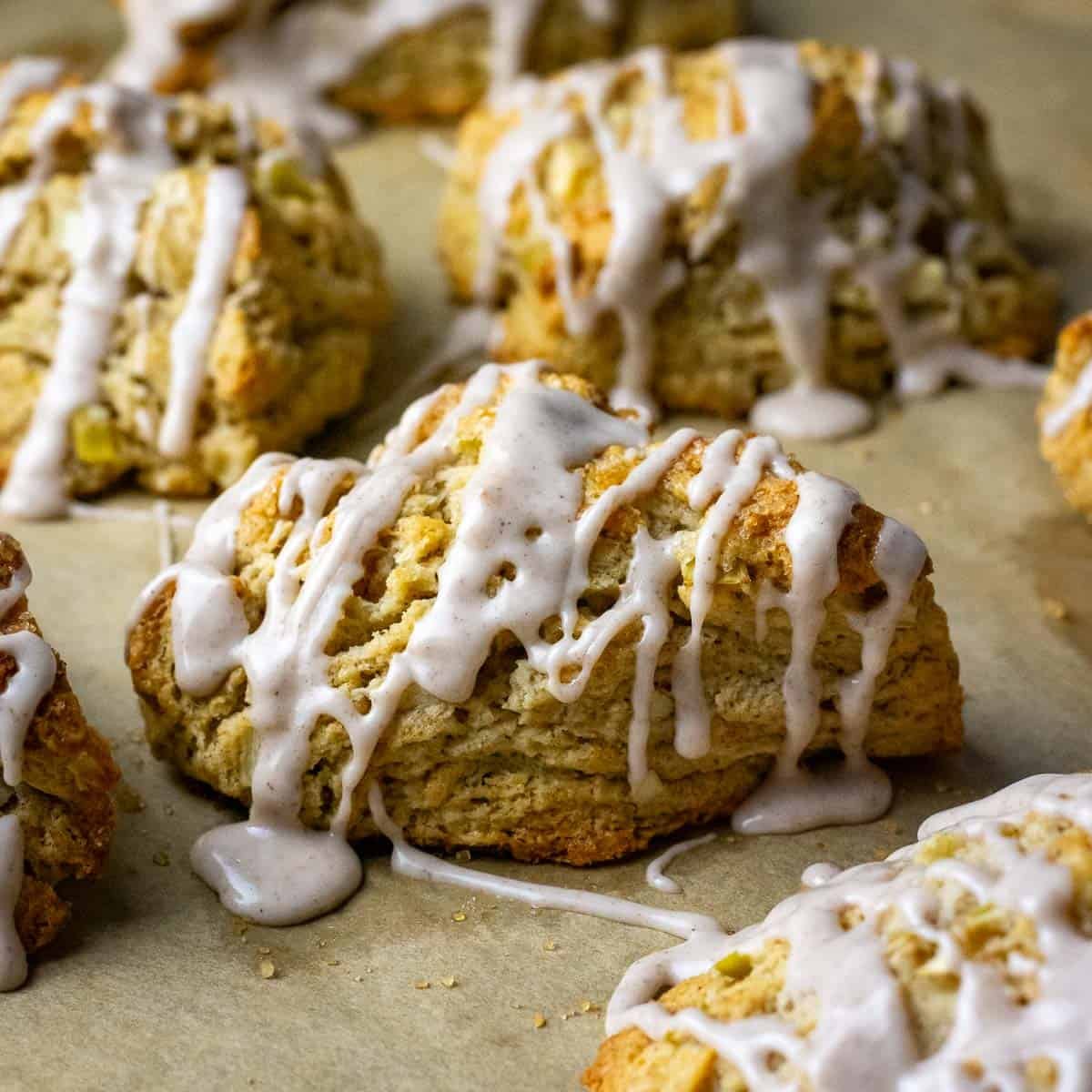 Cinnamon sugar glazed sourdough apple scones on a baking sheet lined with parchment paper.